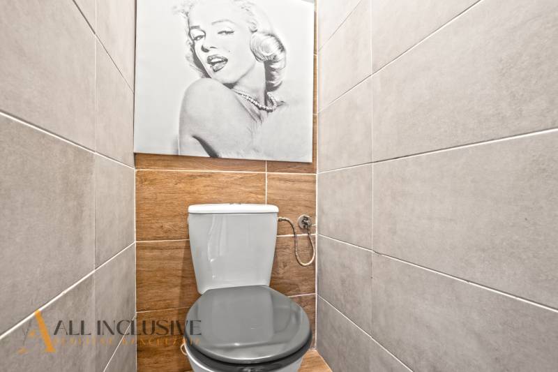 Háromszobás lakás WC-je fa dekor padlóval és fali fotóval.