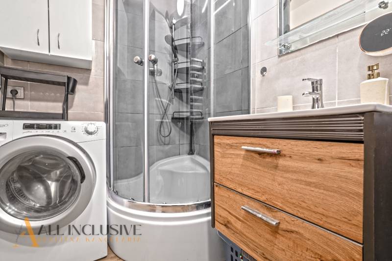 Fürdőszoba mosógéppel, zuhanyzóval és szekrénnyel egy háromszobás lakásban.