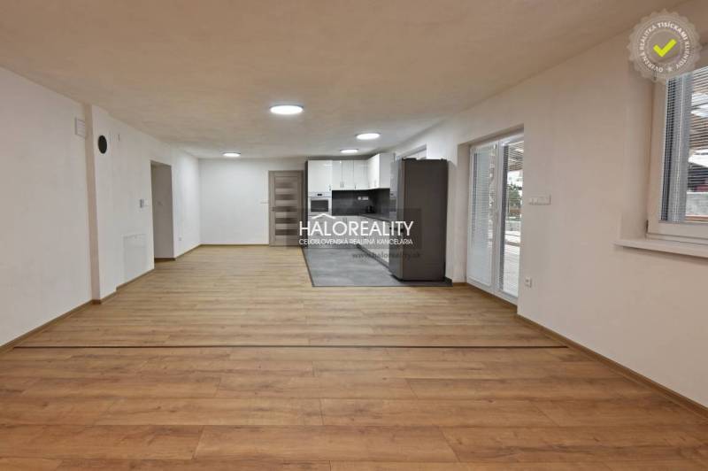 Nappali családi házban konyhával, fa mintás padló, fehér falak.