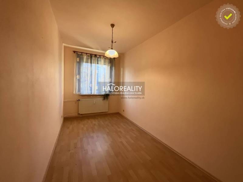 Keskeny világos helyiség ablakkal, függönyökkel és fa dekorációjú padlóval egy háromszobás lakásban.