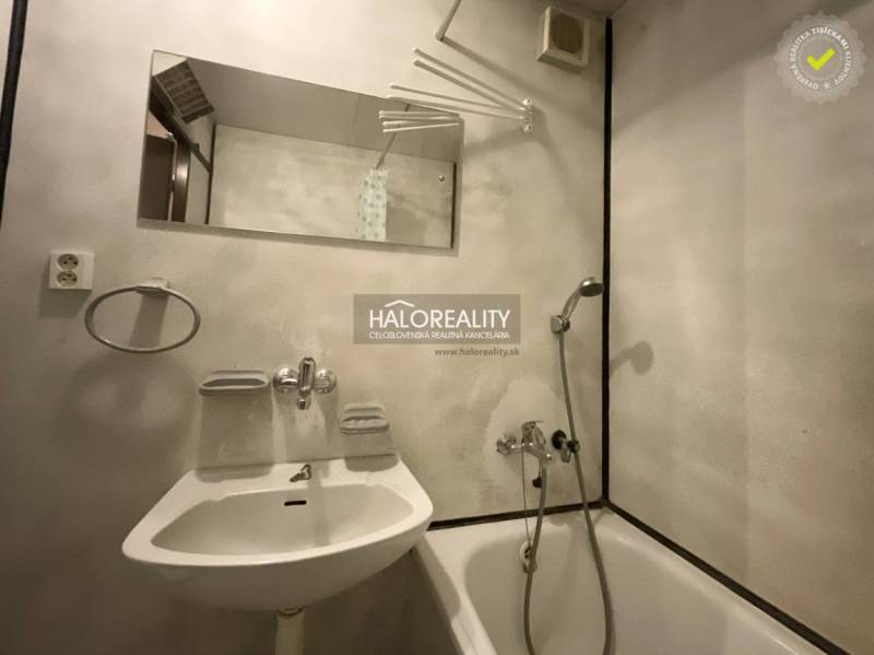 Fürdőszoba egy háromszobás lakásban káddal, tükörrel és fehér mosdóval.