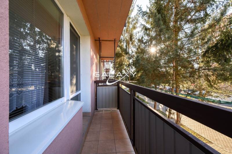 Erkély a Füleki Sládkovičova utcában, zölddel körülvéve, egy 2 szobás lakás része.