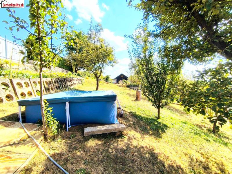 A képen egy kert látható medencével és fákkal, valamint zölddel körülvett házikóval.