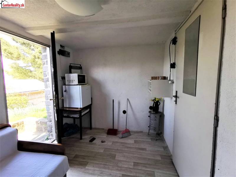 Chata belseje háztartási gépekkel, kanapéval és kilátással a kinti természetre.