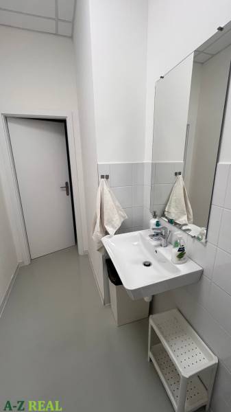 Irodai fürdőszoba mosdóval, törölközőkkel és tisztítószerekkel.