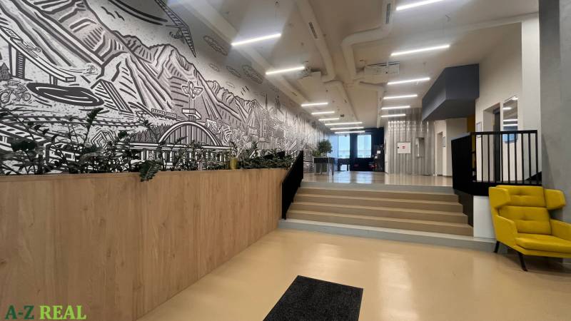 Irodák fa dekor padlóval, lépcsők, szék és egy nagy falfestmény.