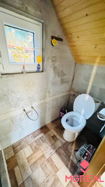 Fa házban lévő WC, fa dekoros padlóval és ablakkal.