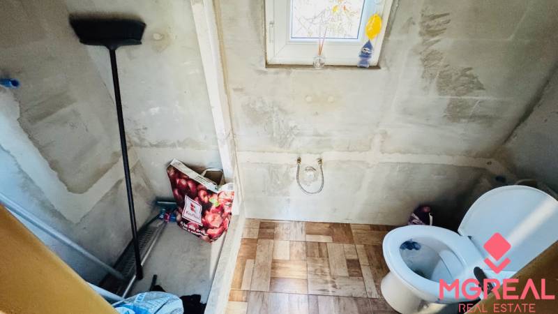 Fürdőszoba a faházban fa dekor padlóval, WC-vel és ablakkal.