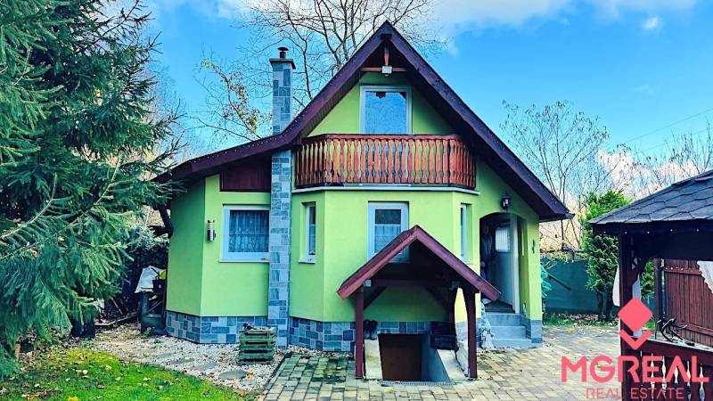 Ház Partizánskeban fa erkéllyel, zölddel körülvéve és kövezett udvarral.