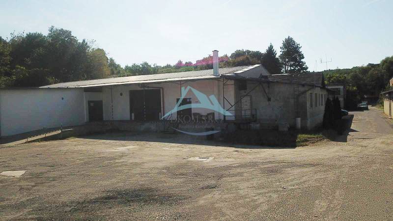 Raktárak és csarnokok a Nagykürtösi Vasút utcában fákkal körülvéve.