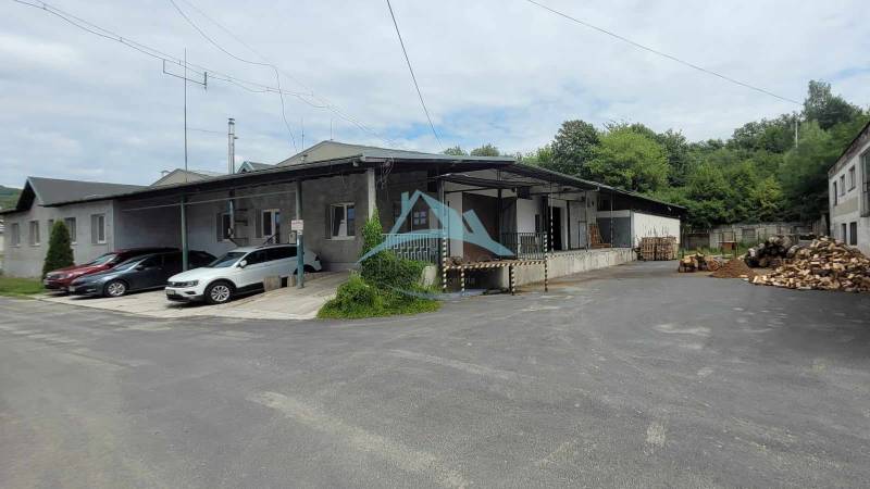 A Vasúti utcában a raktárak és csarnokok mellett áll egy épület autókkal és fával.