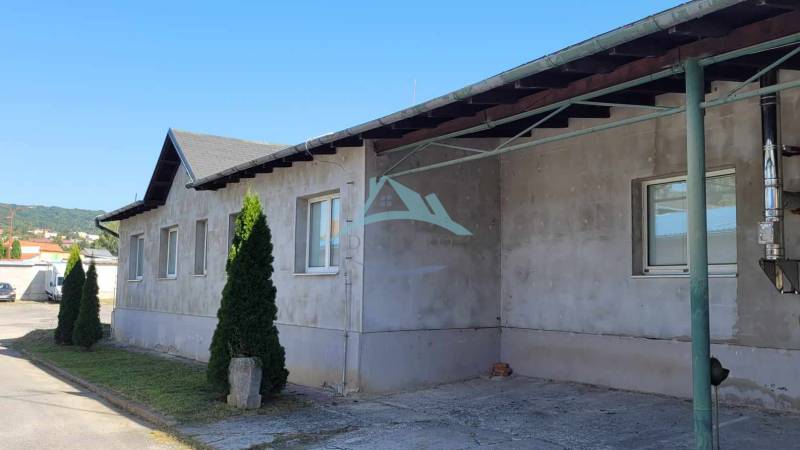 Ipari épület a Vasút utcán, zölddel körülvéve, háttérben csarnokok és raktárak.