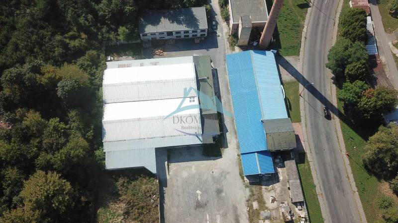 Légi felvétel a csarnokokról és raktárakról a Vasút utca közelében, zöldövezet és földterület által körülvéve.