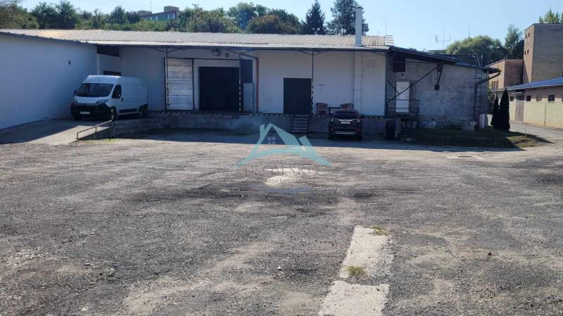 A Vasúti utcában raktárak és csarnokok találhatók, parkolóhelyekkel és autókkal.