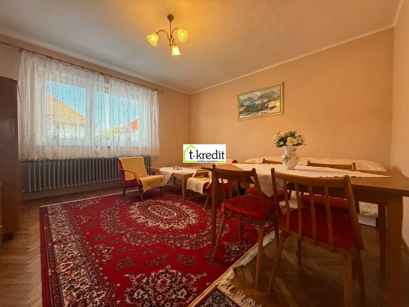 Nappali családi házban szőnyeggel, fa bútorokkal és fa dekorációjú padlóval.