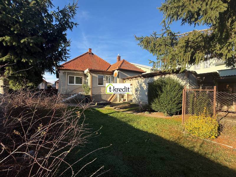 Családi ház Machulincén piros cseréptetővel, kerttel és magas fákkal.