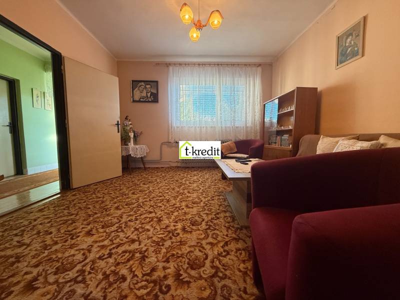 Nappali egy családi házban szőnyegpadlóval, bútorokkal és függönyökkel.