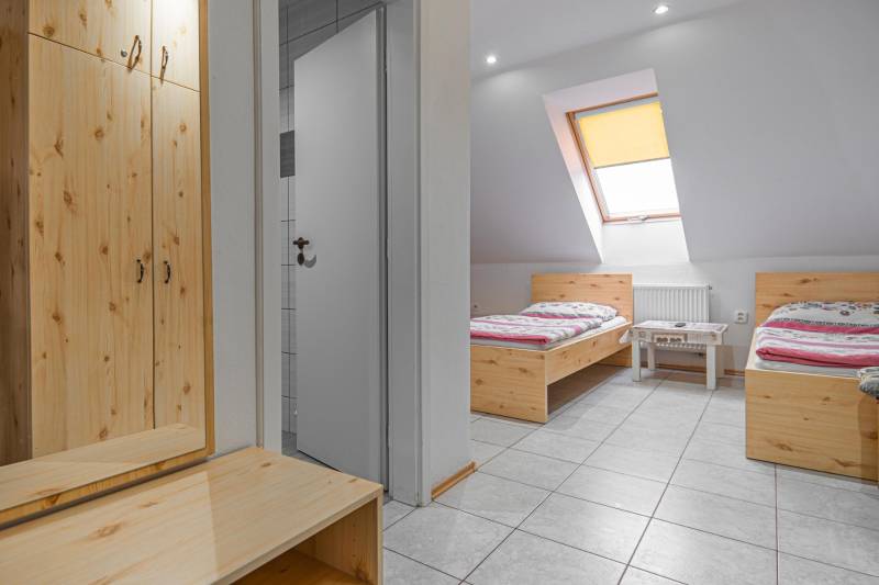 Szállodai és panziós szoba belső tere két ággyal és szekrénnyel, fa dekorációjú padlóval.