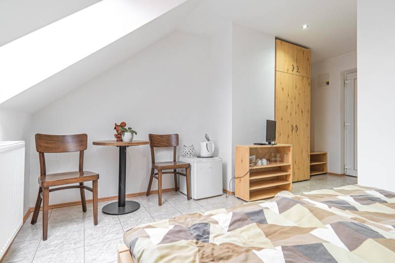 Szoba szállodában és panziókban két székkel, asztallal, szekrénnyel és ággyal.