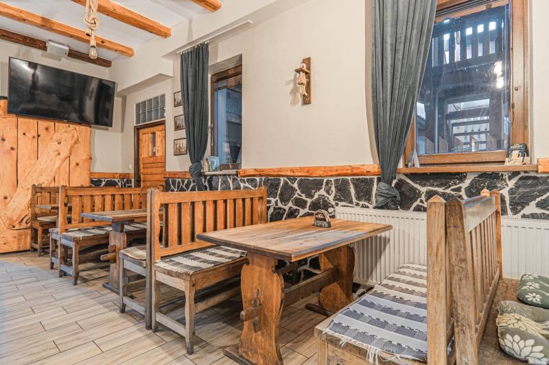 Szállodák és panziók belső tere rusztikus fa padokkal és asztallal, dekoratív kő a falon.