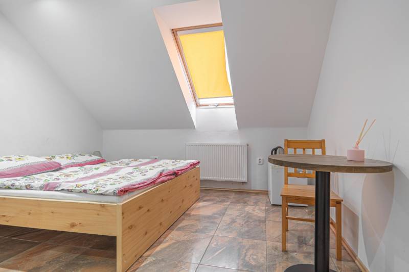 Szoba szállodákban és panziókban faasztallal, virágos ágyneművel és ferde ablakkal.