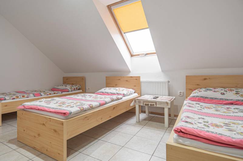 Három ágy színes ágyneművel, asztal, tetőablak szállodákban és panziókban.