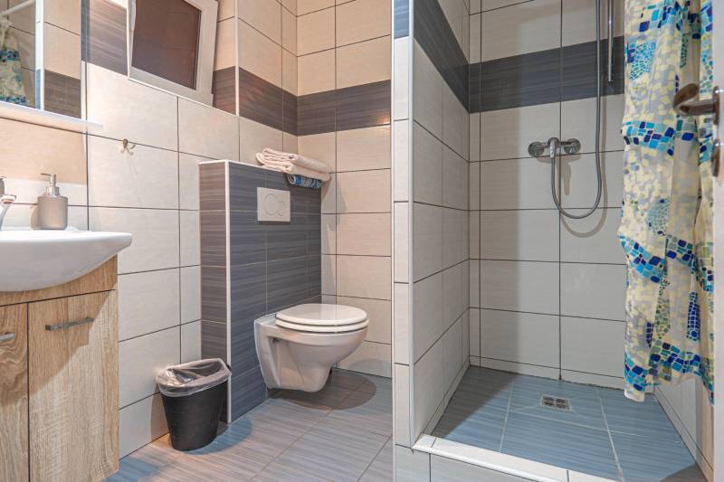 Fürdőszoba a szállodákban és panziókban WC-vel, mosdóval és zuhanyzóval.