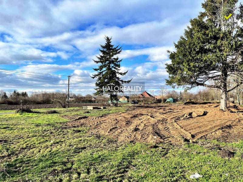 Lakóterületek Ondrejovce-ben füves területtel és fákkal a kék ég alatt.