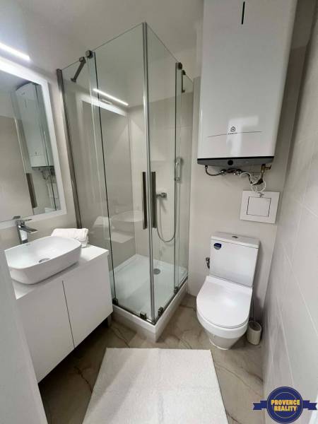 Fürdőszoba egy kétszobás lakásban, modern zuhanyzóval és mosdóval.