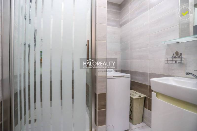 Fürdőszoba mosógéppel és zuhanyzóval egy háromszobás lakásban, világos csempék, tiszta dizájn.