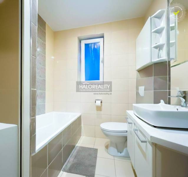 Fürdőszoba káddal és mosdóval egy kétszobás lakásban, világos csempe dominál.