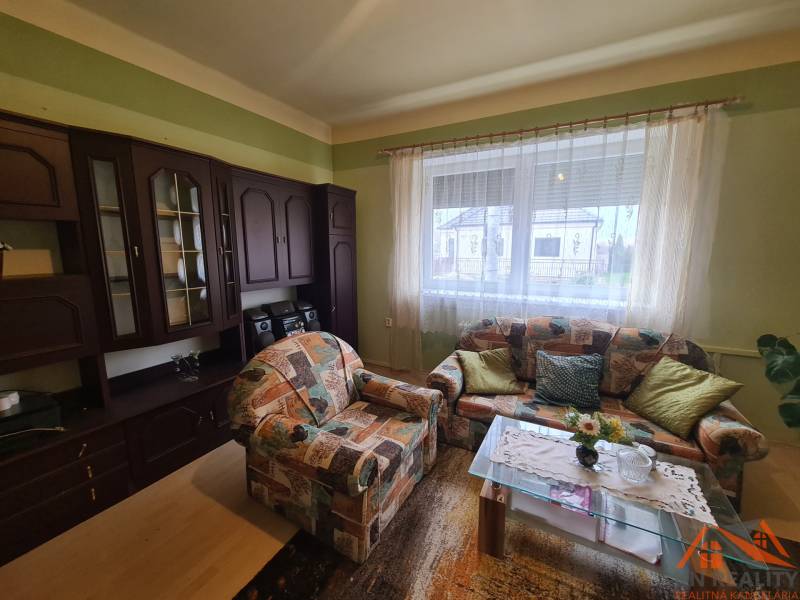 Családi ház nappalija színes kanapéval és sötét nappali szekrénnyel.