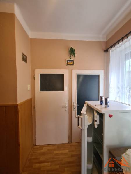 Családi ház belső tere két ajtóval, hűtőszekrénnyel és fa dekorációjú padlóval.