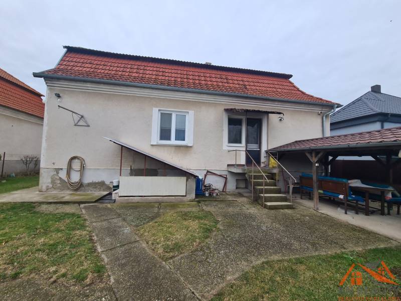 Családi ház Hurbanovóban piros tetővel és kerti kiülővel.