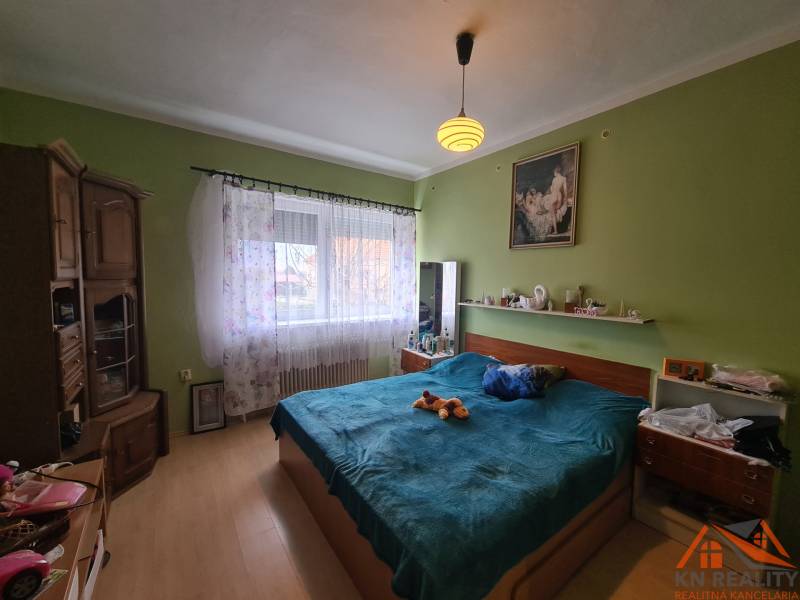 Hálószoba családi házban fa dekorációjú padlóval és ággyal.