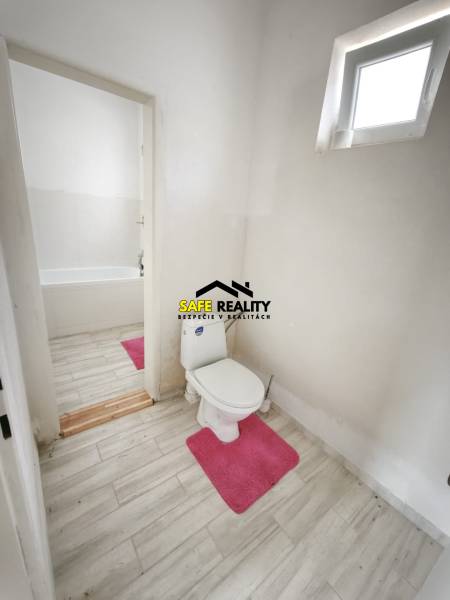 Fürdőszoba családi házban WC-vel, káddal és fa dekorációjú padlóval.