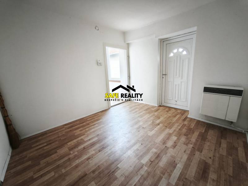 Családi ház belső tere fa dekorációjú padlóval és fehér falakkal.