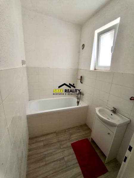 Fürdőszoba családi házban káddal, mosdóval és fa mintázatú padlóval.