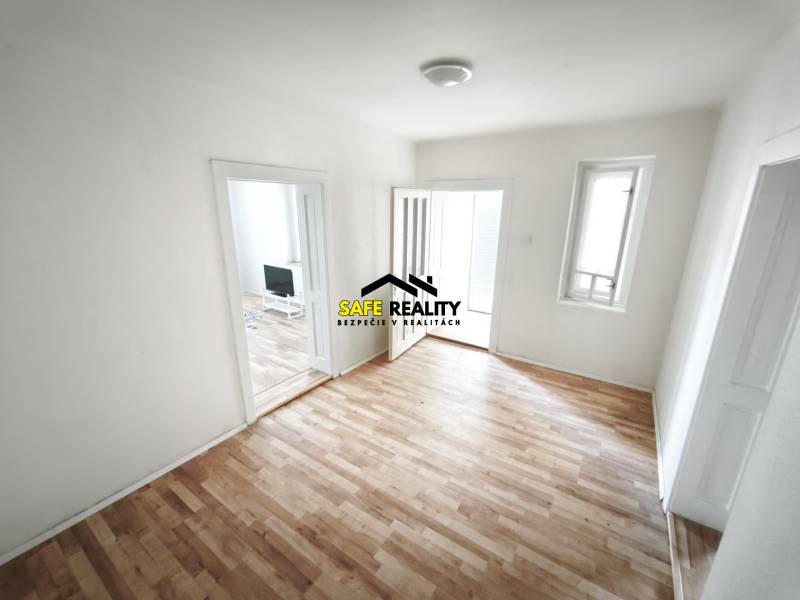 Szoba egy családi házban, fa dekoros padlóval és egyszerű berendezéssel.