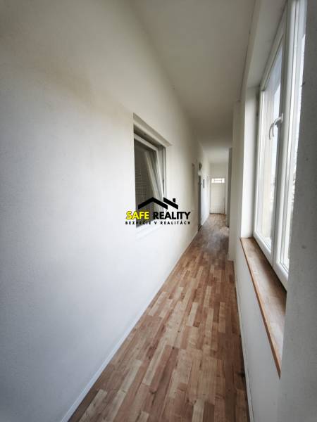 Folyosó egy családi házban, fa dekoros padlóval és nagy ablakokkal.