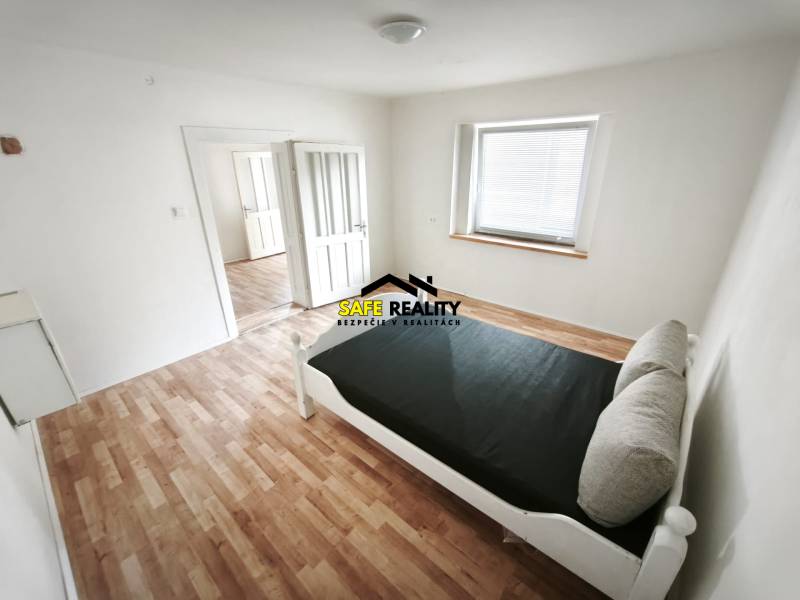 Világos szoba ággyal, fa dekorációjú padlóval, családi házban.