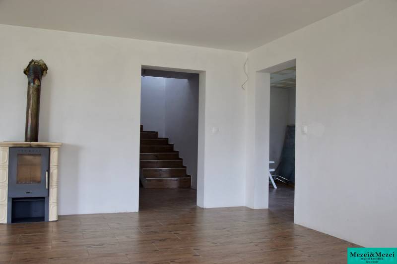 Családi ház belső tere kandallóval, lépcsővel és fa dekorációjú padlóval.