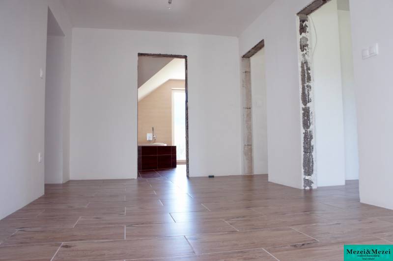 Családi ház belső tere fa dekorációjú padlóval és fedetlen építési nyílásokkal.