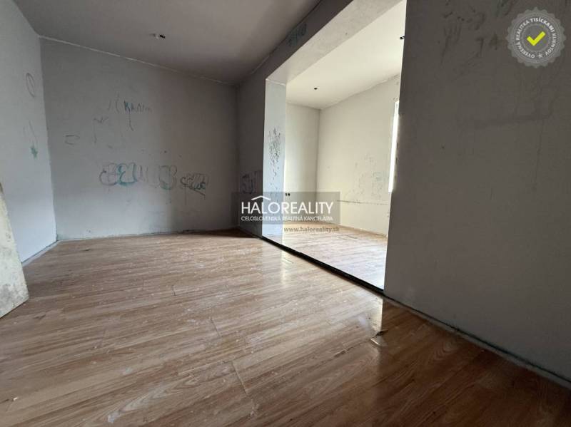 Szoba családi házban, fa mintázatú padlóval és egyszerű falakkal.