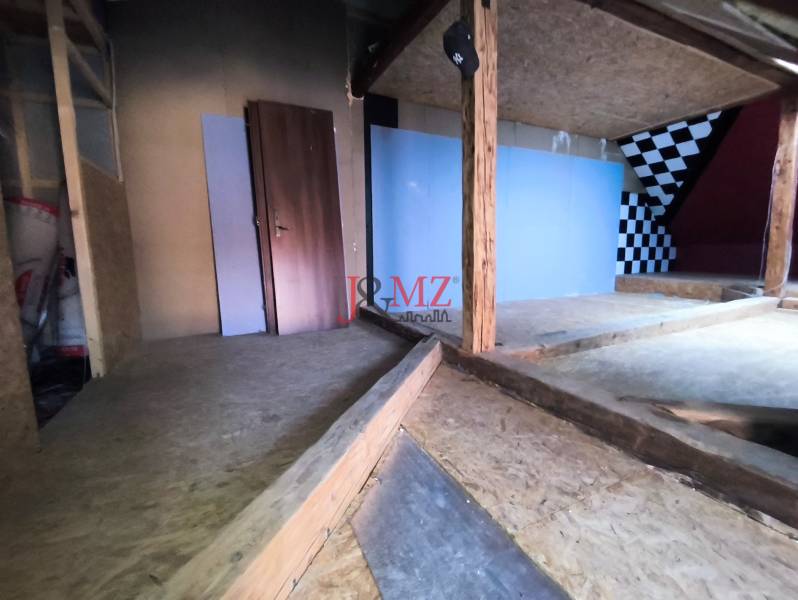 Családi ház tetőtéri helyisége fa elemekkel, sakktáblaszerű fal.