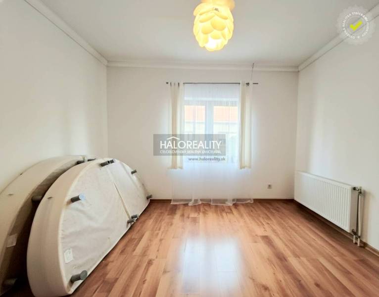 Egy családi házban lévő szoba fa dekorációjú padlóval, világos díszítéssel és nagy ablakkal.