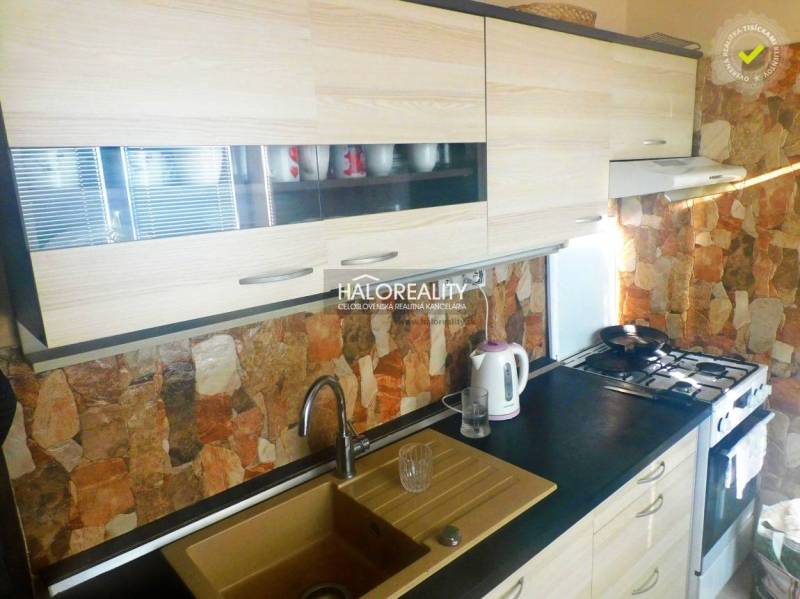 Szoba egy kétszobás lakásban fa dekoros padlóval, televízióval és beépített szekrényekkel.