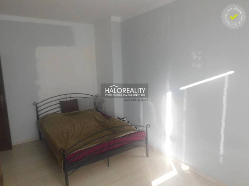 Hálószoba fém ággyal és fehér falakkal egy kétszobás lakásban.