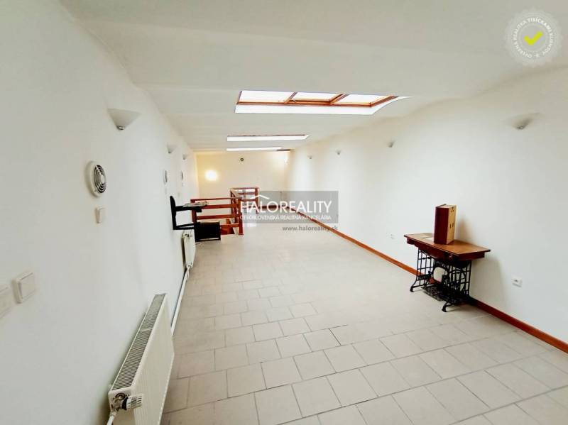 Világos folyosó egy családi házban fehér falakkal és tetőablakokkal.