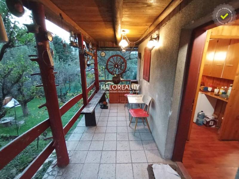 Külső terasz fa korláttal és kerttel a házikó mellett, nyugalmat kínál.